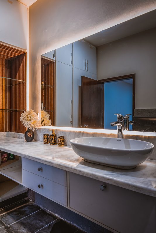 A stone vanity and backlit mirror at Shoaib Residence.